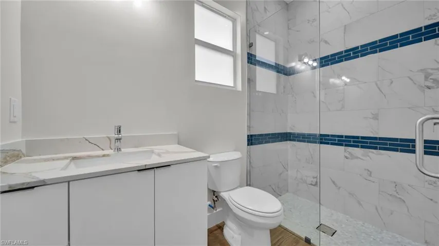 Bathroom with vanity and a marble finish shower