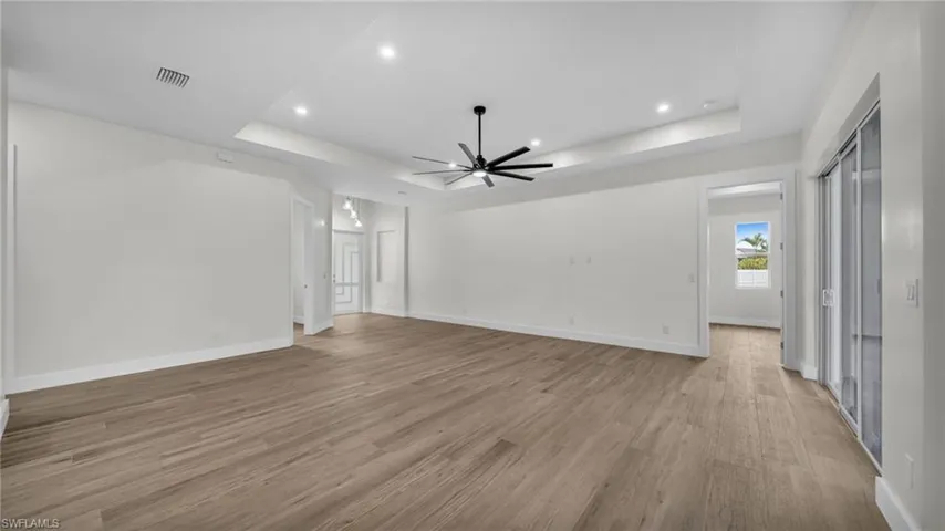 Unfurnished living room featuring a tray ceiling, recessed lighting, light wood-style flooring, and a ceiling fan