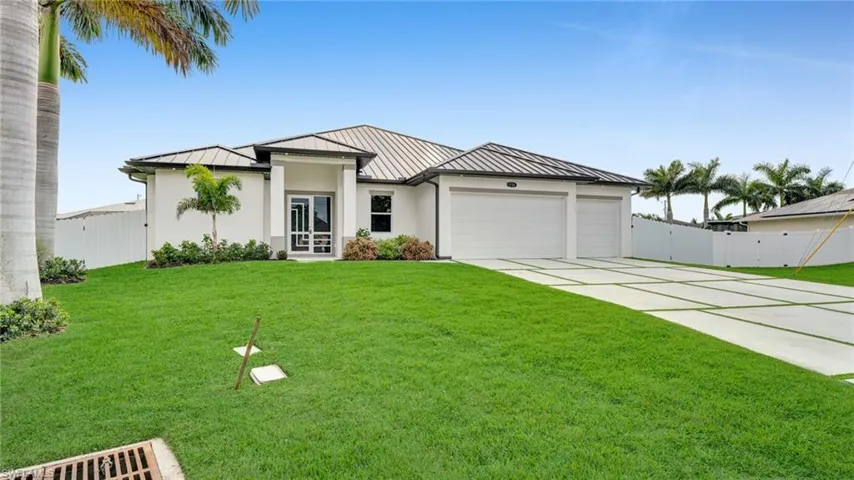 View of front of home with a standing seam roof, a metal roof, a garage, and driveway