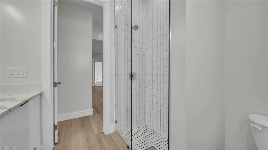 Bathroom with light wood-style floors, a shower stall, and vanity