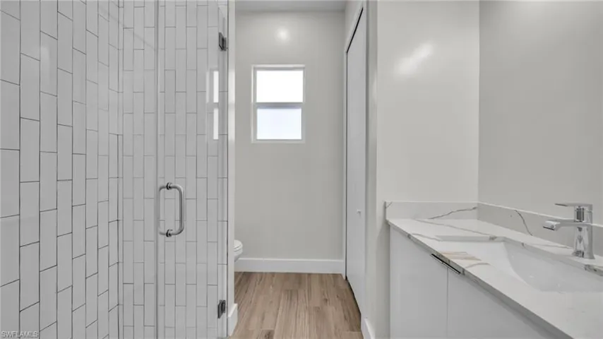 Full bathroom with vanity, a shower stall, and light wood-style flooring