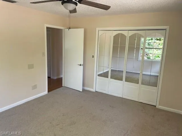 Unfurnished bedroom featuring carpet floors, a closet, baseboards, and a textured ceiling