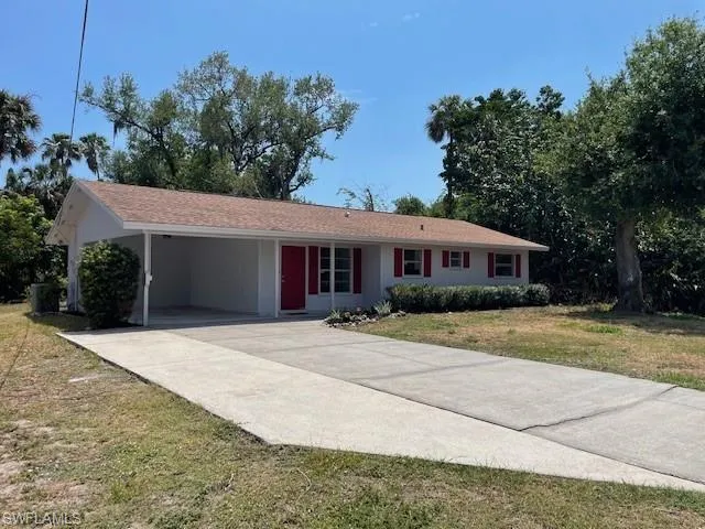 Ranch-style home featuring driveway, a carport, and a front lawn
