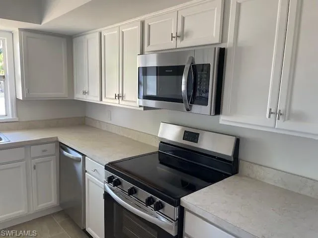 Kitchen featuring appliances with stainless steel finishes, white cabinets, and light countertops