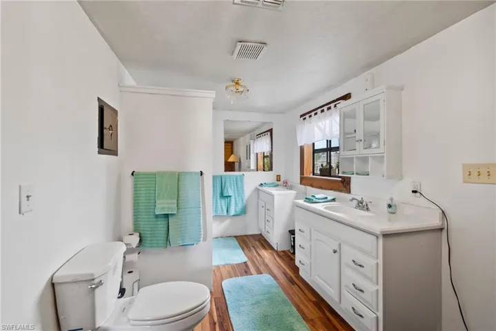 Bathroom featuring wood-type flooring, oversized vanity, and toilet