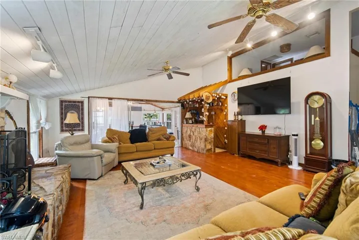 Living room with hardwood / wood-style flooring, ceiling fan, vaulted ceiling, and rail lighting