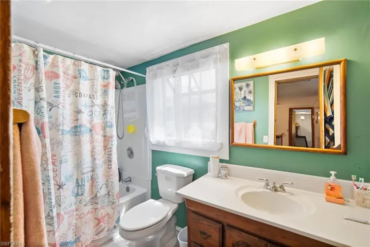 Full bathroom with shower / bathtub combination with curtain, toilet, and vanity