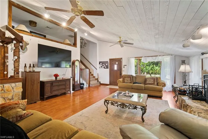 Living room featuring wooden ceiling, light wood-type flooring, vaulted ceiling, and ceiling fan