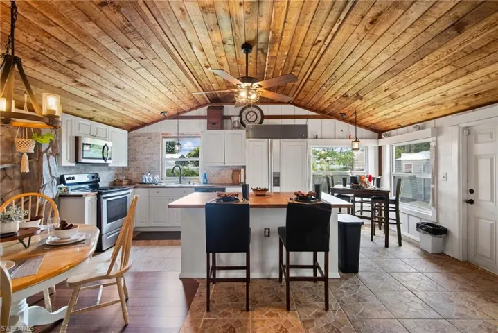 Kitchen with a wealth of natural light, wooden ceiling, tasteful backsplash, and vaulted ceiling
