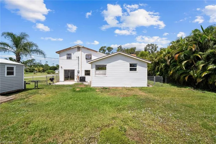 Rear view of property with a patio, central AC unit, and a lawn