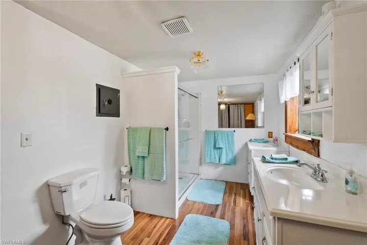 Bathroom featuring walk in shower, oversized vanity, hardwood / wood-style flooring, and toilet