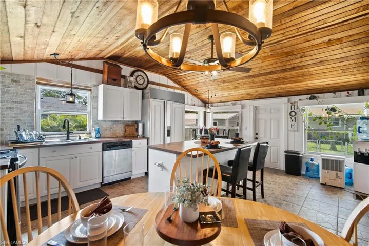 Dining space with sink, light tile flooring, wood ceiling, and lofted ceiling