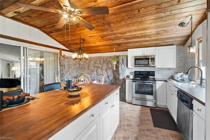 Kitchen with stainless steel appliances, butcher block countertops, white cabinetry, and wooden ceiling