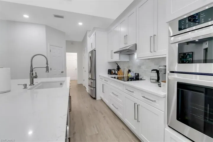 Kitchen featuring visible vents, under cabinet range hood, a sink, appliances with stainless steel finishes, and white cabinets