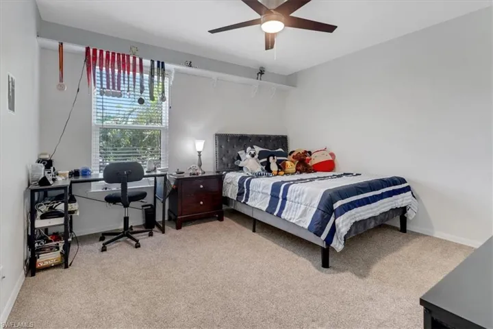 Carpeted bedroom with a ceiling fan and baseboards