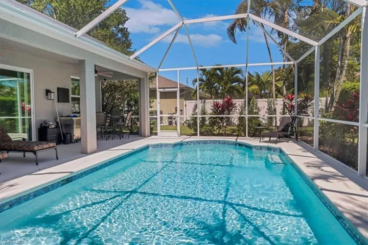 View of swimming pool featuring glass enclosure, a patio, a ceiling fan, and a fenced in pool