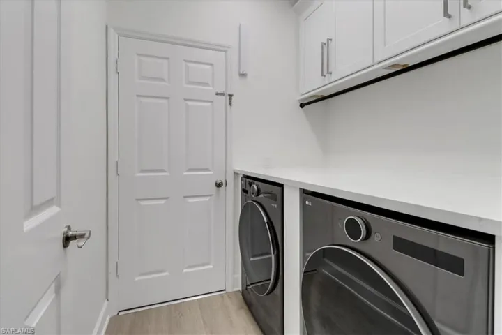 Custom Washroom with light wood-style flooring, cabinet space, and washing machine and clothes dryer