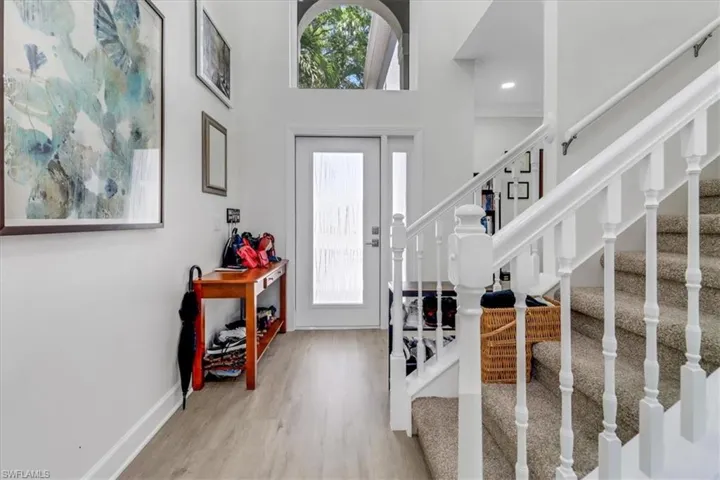 Entrance foyer with a towering ceiling, stairs, baseboards, and wood finished floors
