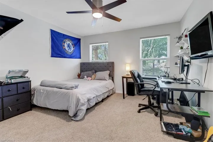 Carpeted bedroom featuring multiple windows and ceiling fan