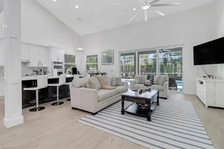 Living area featuring high vaulted ceiling, light wood-type flooring, and ceiling fan