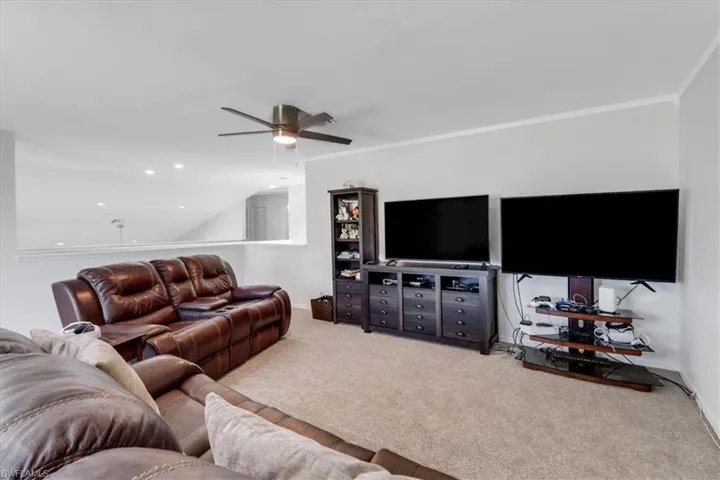 Carpeted living room featuring ornamental molding, recessed lighting, baseboards, and ceiling fan