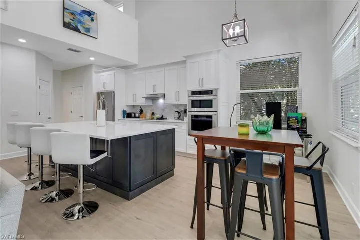 Kitchen featuring under cabinet range hood, a kitchen island, appliances with stainless steel finishes, and white cabinets