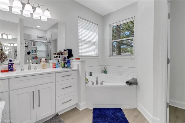 Full bath featuring a garden tub, vanity, wood finished floors, and a shower stall