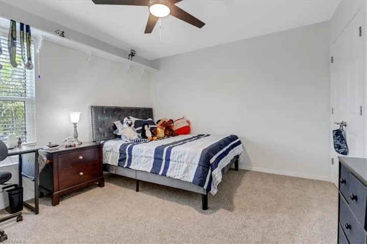 Bedroom with baseboards, light colored carpet, and ceiling fan