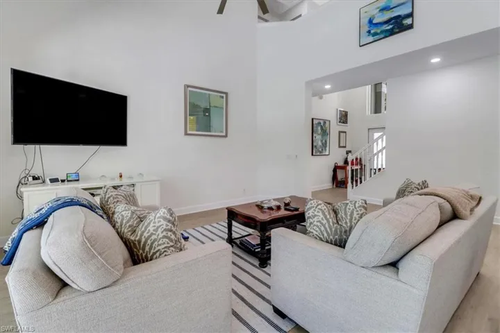 Living area with light wood-style flooring, recessed lighting, baseboards, a towering ceiling, and stairs