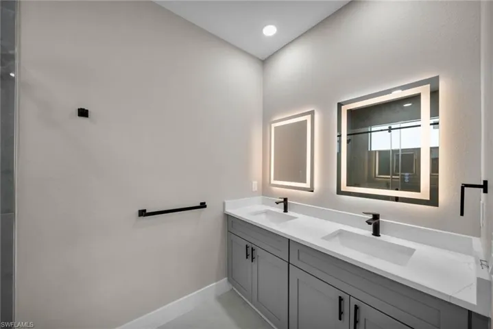 Full bath with double vanity, an enclosed shower, and light tile patterned floors