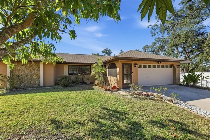 Single story home featuring stucco siding, a front lawn, driveway, and an attached garage