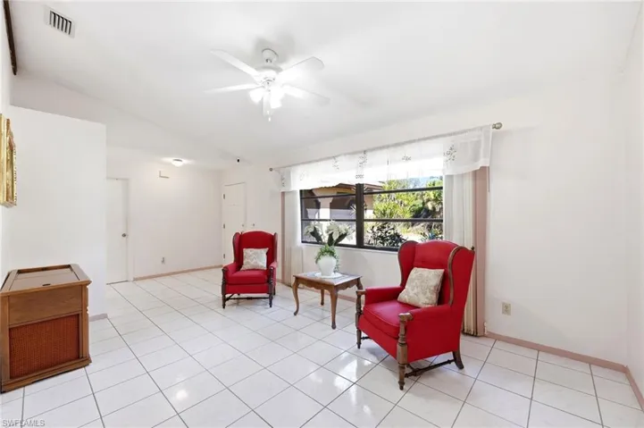 Living area with lofted ceiling, a ceiling fan, and light tile patterned floors
