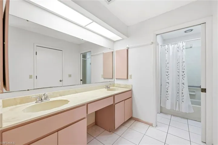 Full bathroom featuring shower / bath combo, double vanity, and light tile patterned floors
