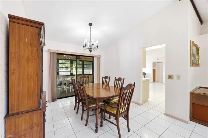 Dining space with vaulted ceiling, light tile patterned floors, and a chandelier