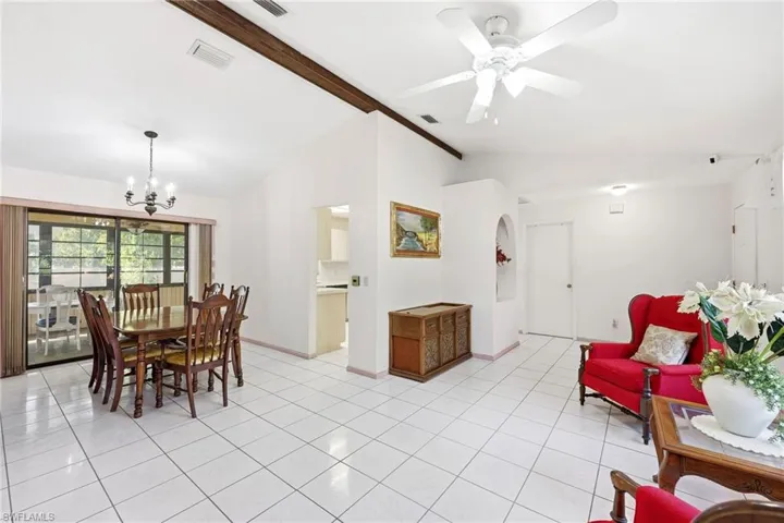 Dining room with a chandelier, beamed ceiling, light tile patterned floors, high vaulted ceiling, and a ceiling fan