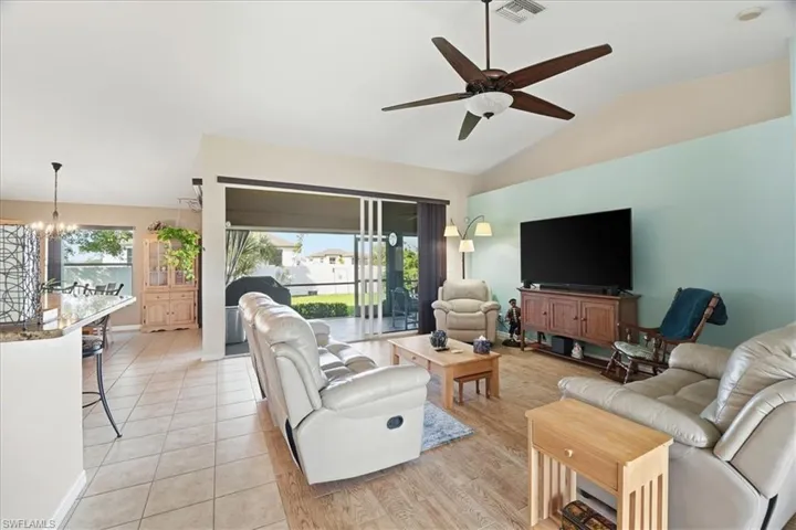 Living room with vaulted ceiling, a chandelier, a ceiling fan, and light tile patterned floors