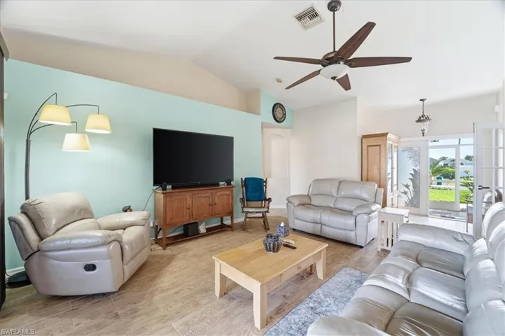 Living area featuring vaulted ceiling, ceiling fan, wood finished floors, and arched walkways