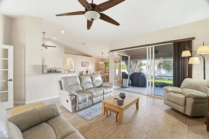 Living room with a ceiling fan, lofted ceiling, light wood finished floors, arched walkways, and recessed lighting