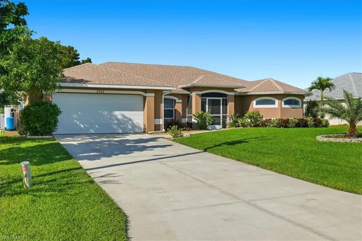 View of front of property featuring concrete driveway, stucco siding, a front lawn, roof with shingles, and a garage