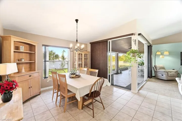 Dining space featuring light tile patterned floors, vaulted ceiling, and a chandelier