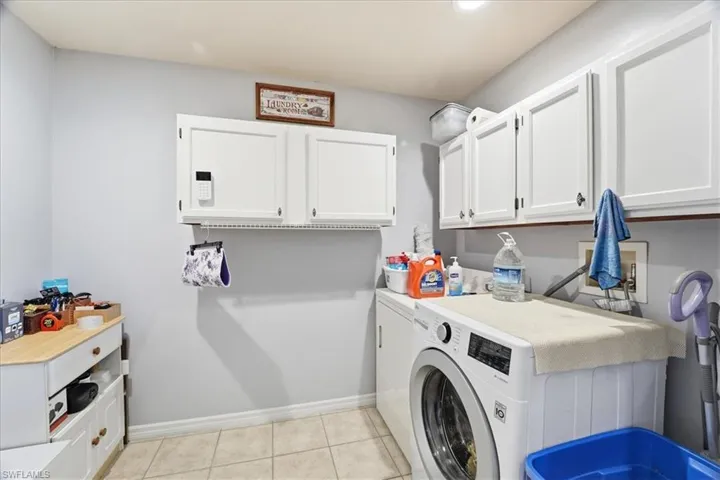Washroom featuring separate washer and dryer, light tile patterned floors, and cabinet space