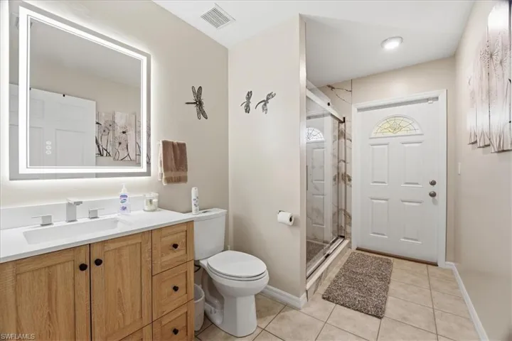 Full bath with vanity, a stall shower, and light tile patterned flooring