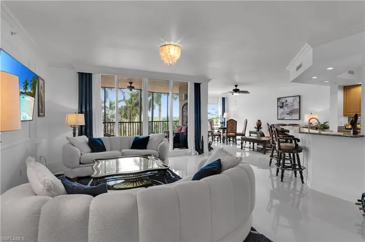 Living area featuring ceiling fan, ornamental molding, a wall of windows, and a chandelier