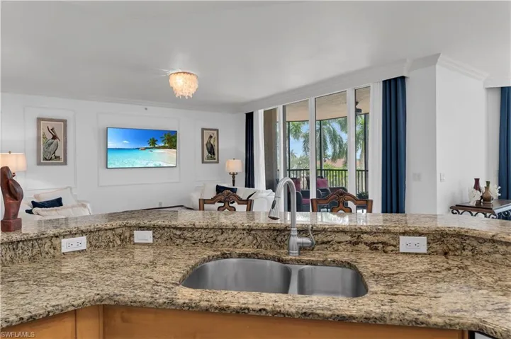 Kitchen featuring crown molding, light stone counters, open floor plan, and a chandelier