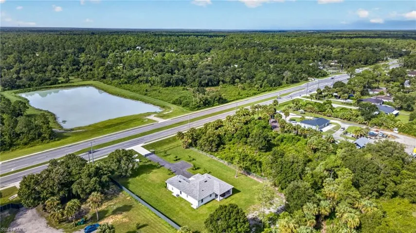 Expansive property featuring a large body of water, direct road frontage, a paved driveway, and surrounding green space