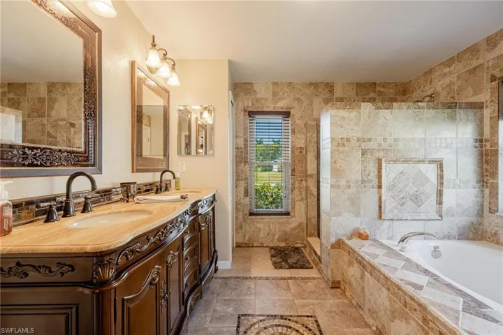 Bathroom with tile walls, double vanity, tile flooring, and plus walk in shower