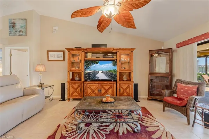 Living room with lofted ceiling, light tile flooring, and ceiling fan