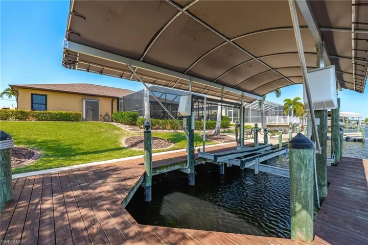 Dock area with a yard, glass enclosure, and a water view