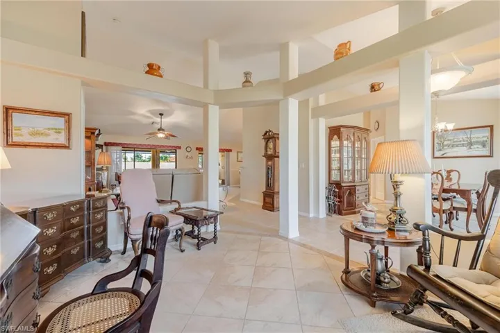 Sitting room featuring a high ceiling, light tile floors, and ceiling fan with notable chandelier