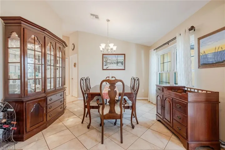Dining room featuring a notable chandelier, lofted ceiling, and light tile flooring